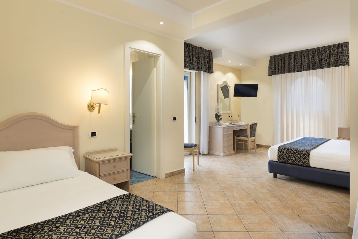 Ein Hotelzimmer mit einem großen Bett, einem Schreibtisch, einem Sessel und einem Fernseher.