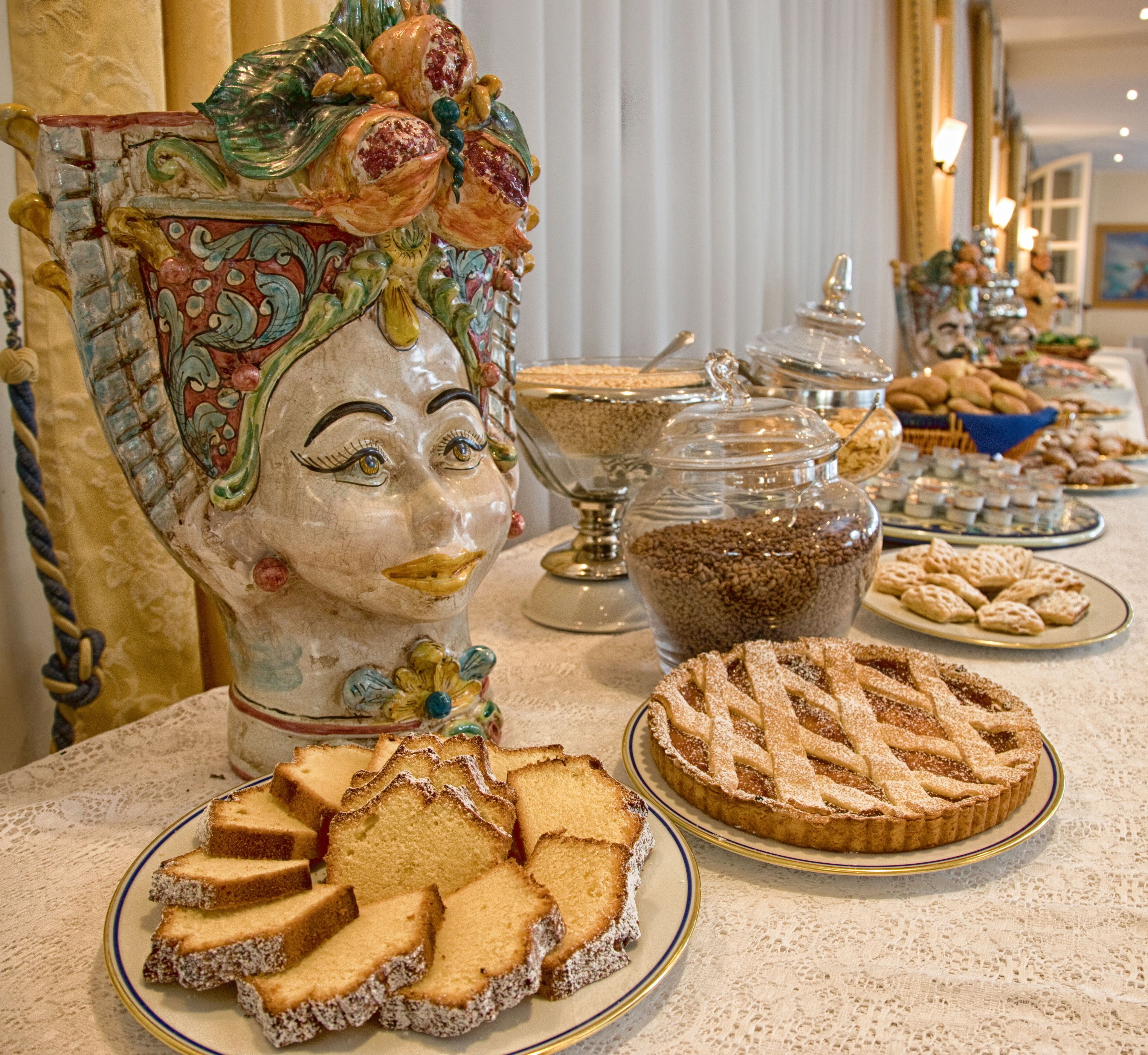 Una mesa de buffet con diversos alimentos, incluyendo una tarta de celosía y porciones de pastel.