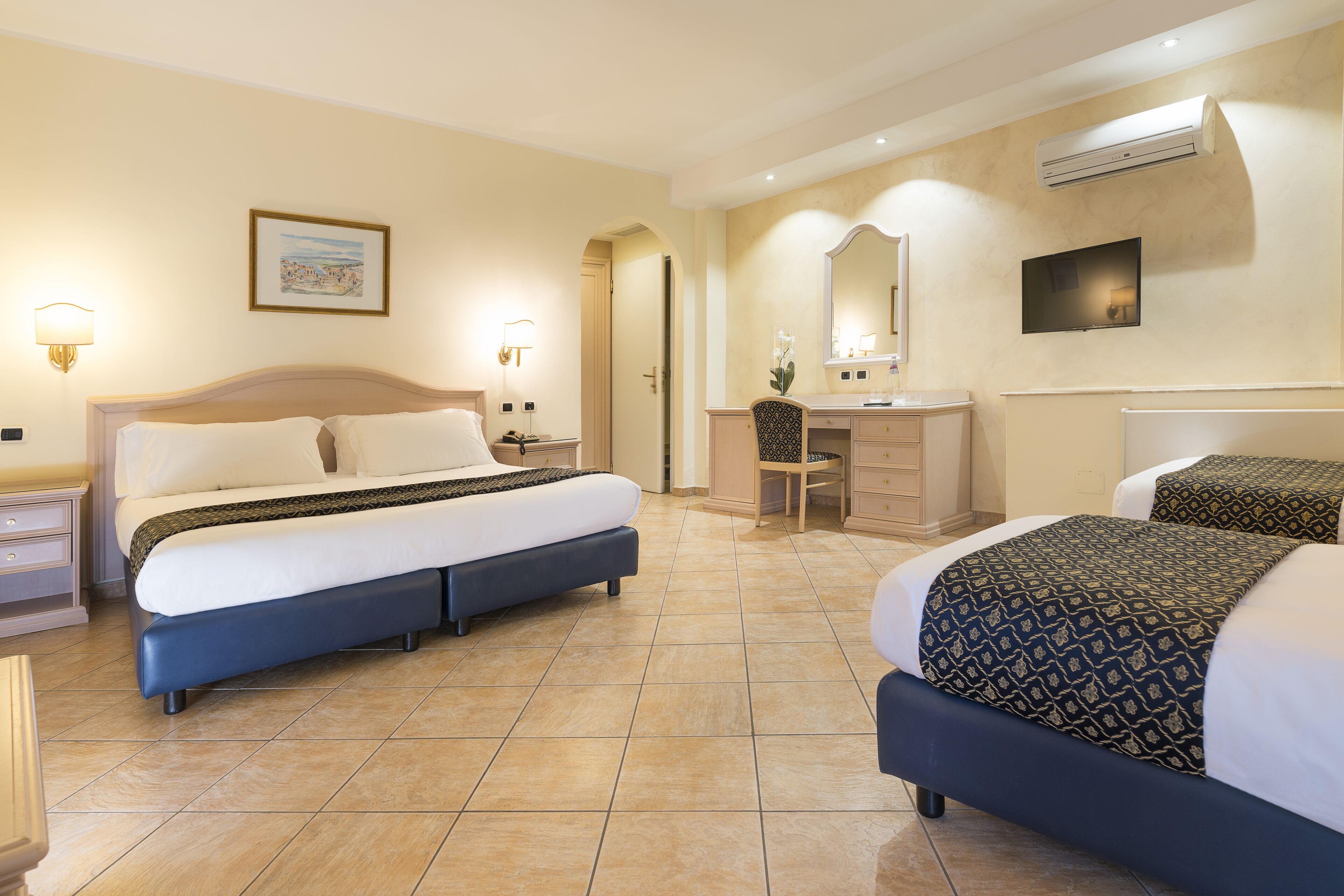 Une chambre d’hôtel avec un lit double, un bureau, une chaise et un téléviseur.