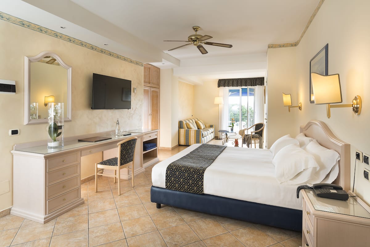 Ein Hotelzimmer mit Bett, Schreibtisch, Stuhl und Fernseher an der Wand.