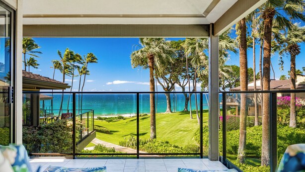 A balcony with a view of the ocean, palm trees, and a well-maintained lawn. - Wailea Elua- CoralTree Residence Collection (Kihei)