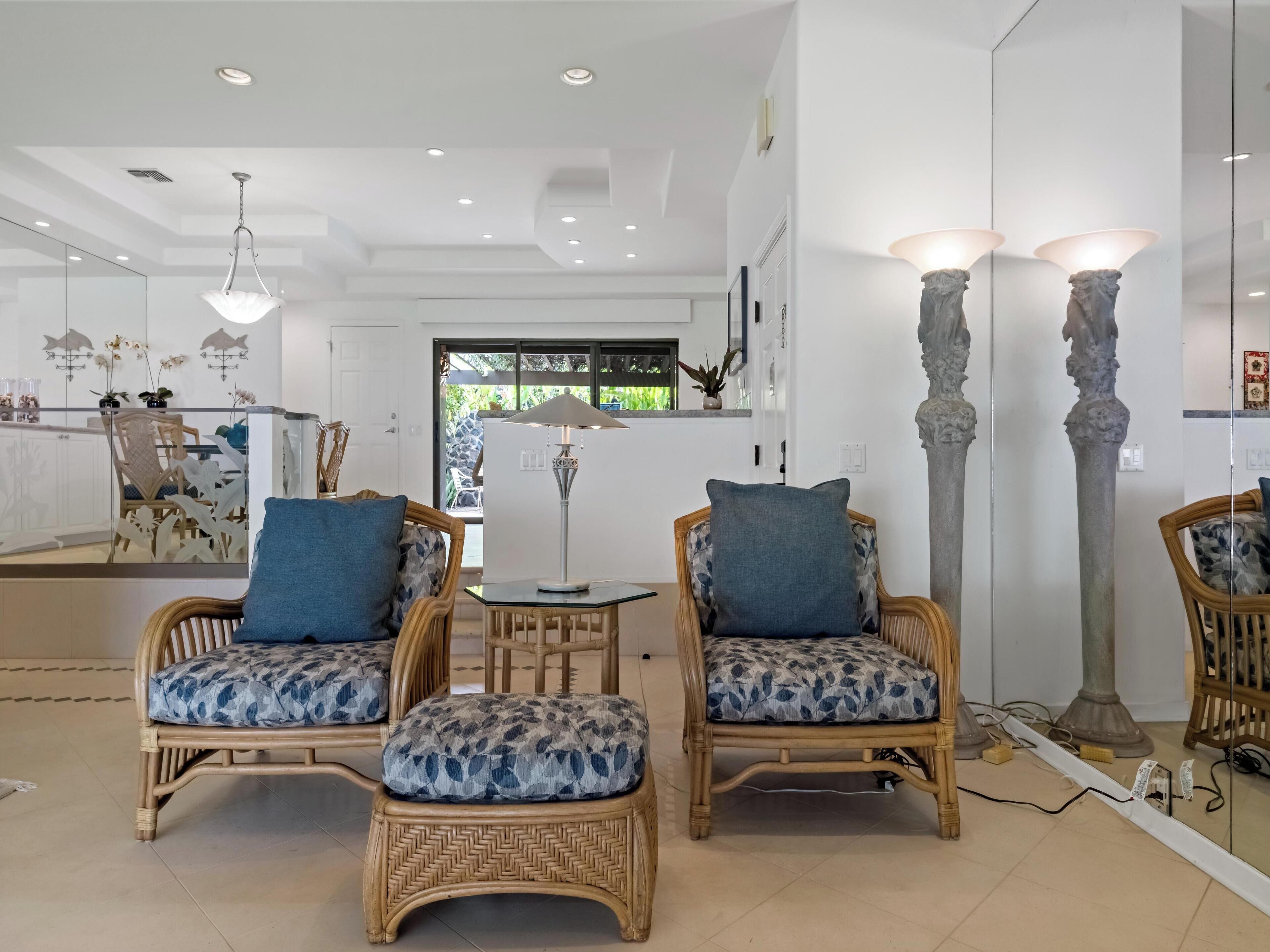 A modern living room with wicker furniture, a glass partition, and a large mirror.