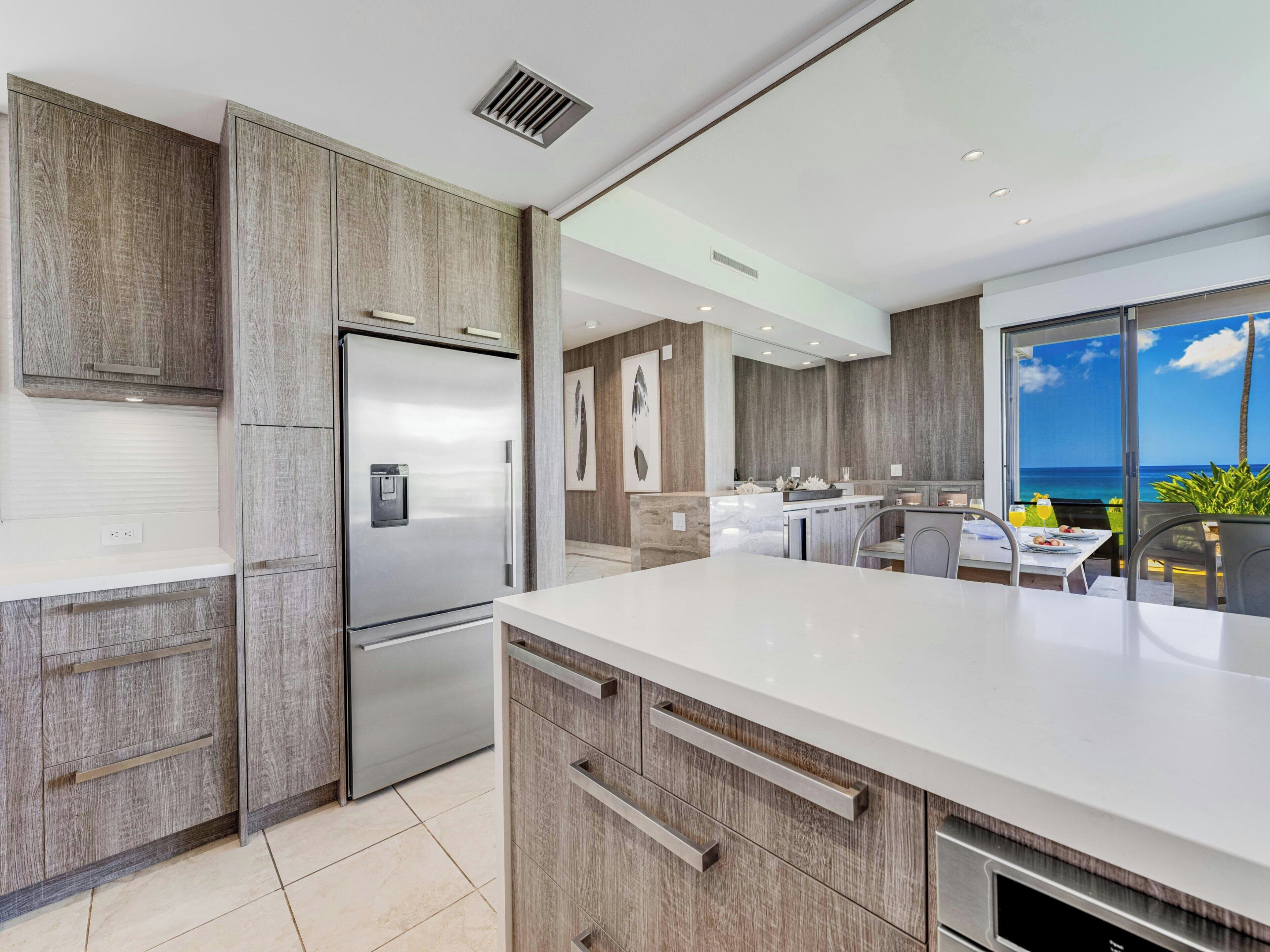 A modern kitchen with a built-in refrigerator, wooden cabinetry, and a large island with a sink.