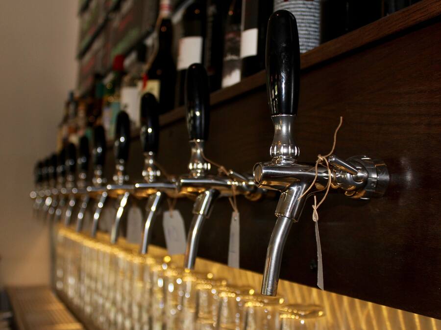 A row of beer taps with labels, mounted on a wooden bar counter.