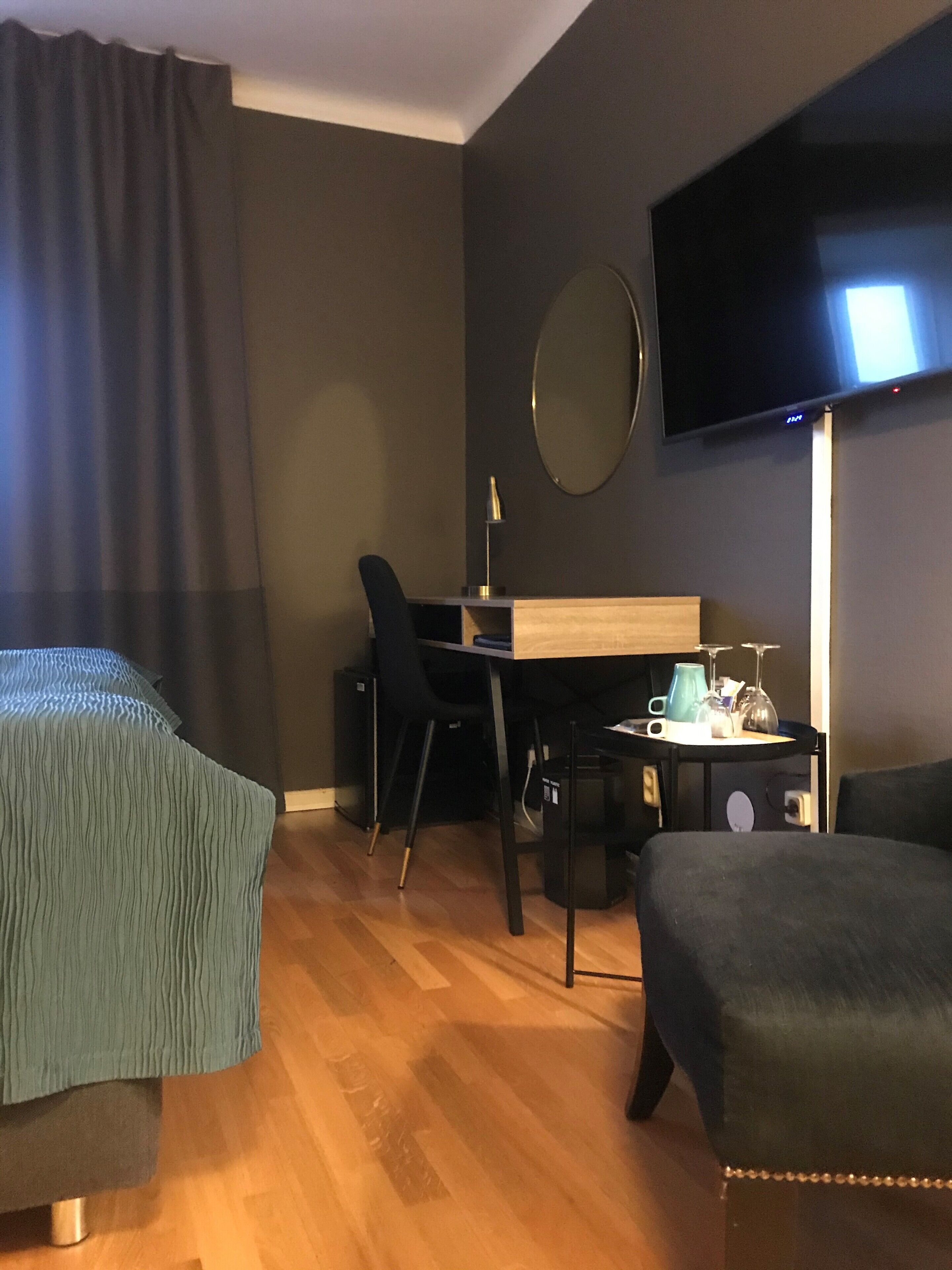 A hotel room with a bed, a desk with a chair, a TV, and a coffee table.