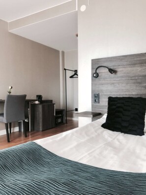 Ein modernes Schlafzimmer mit Bett, Nachttisch, Lampe und Schreibtisch mit Stuhl.