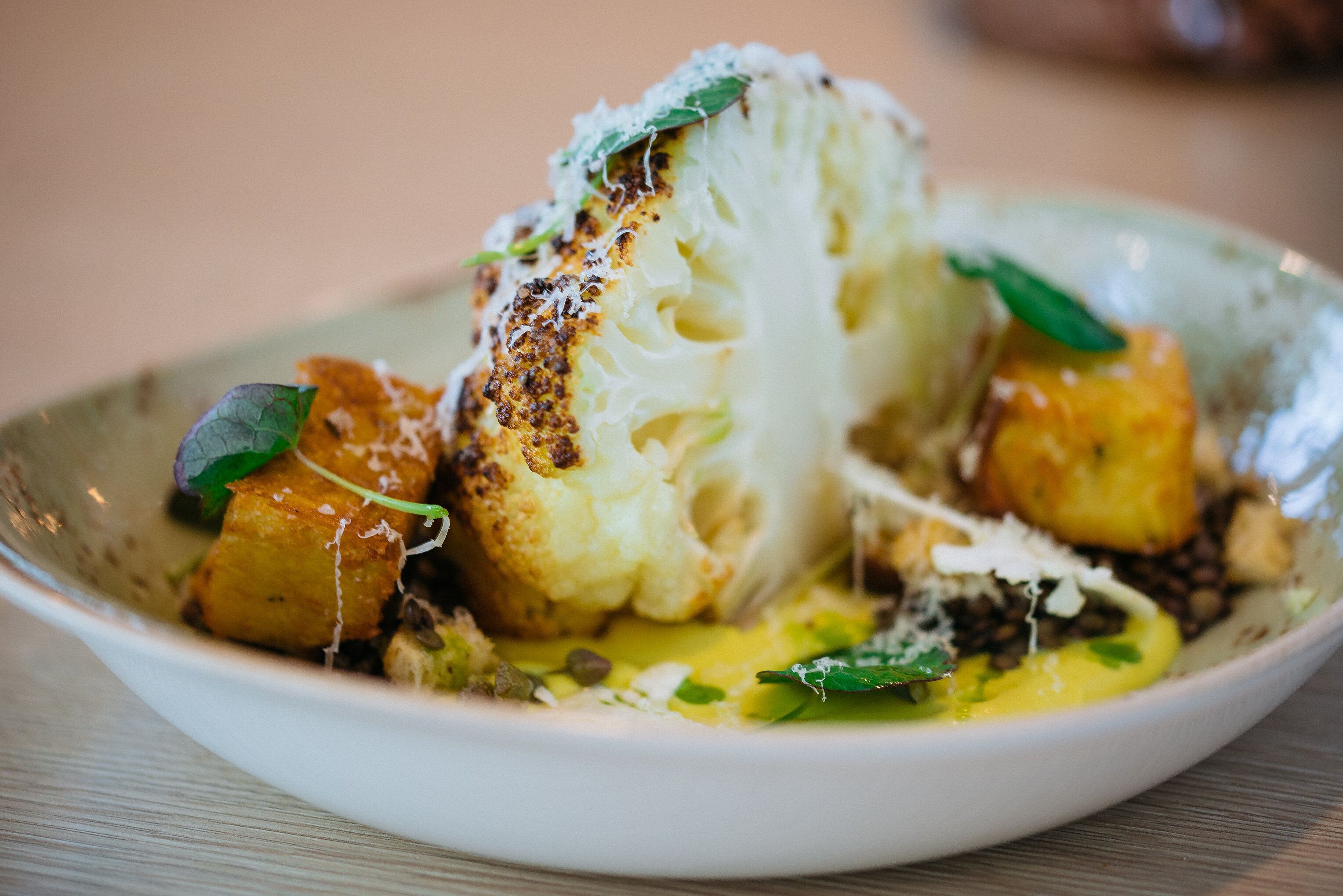 A bowl of food with cauliflower and other vegetables.