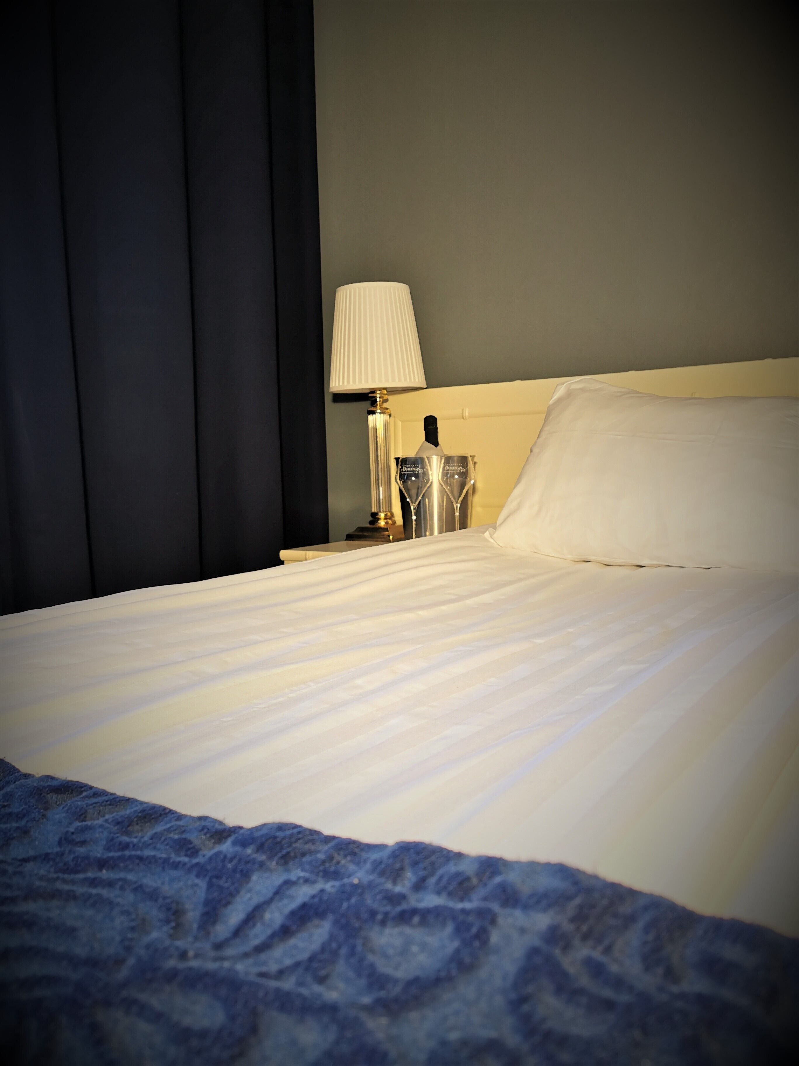 Un lit bien fait, avec un oreiller blanc et une couverture bleue.