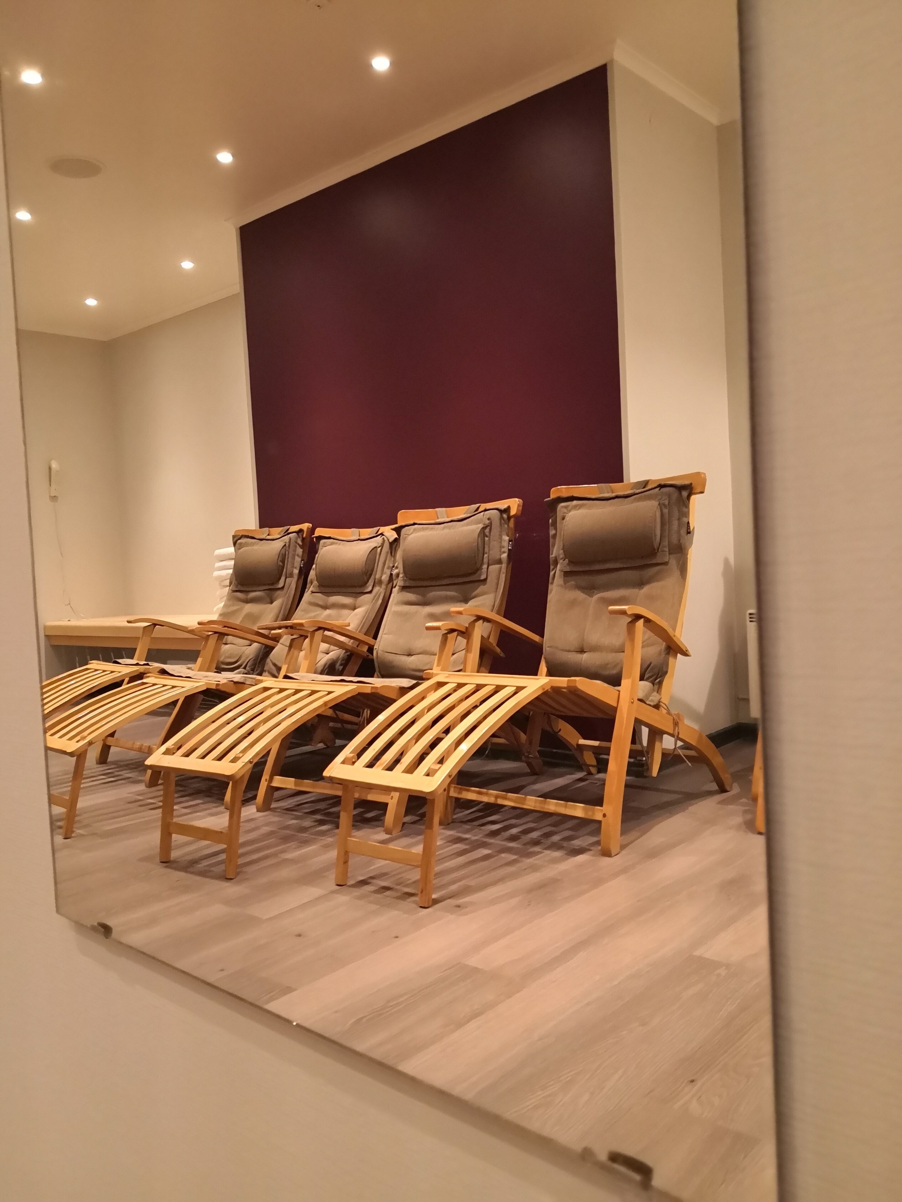 A room with wooden lounge chairs and a dark-colored wall.