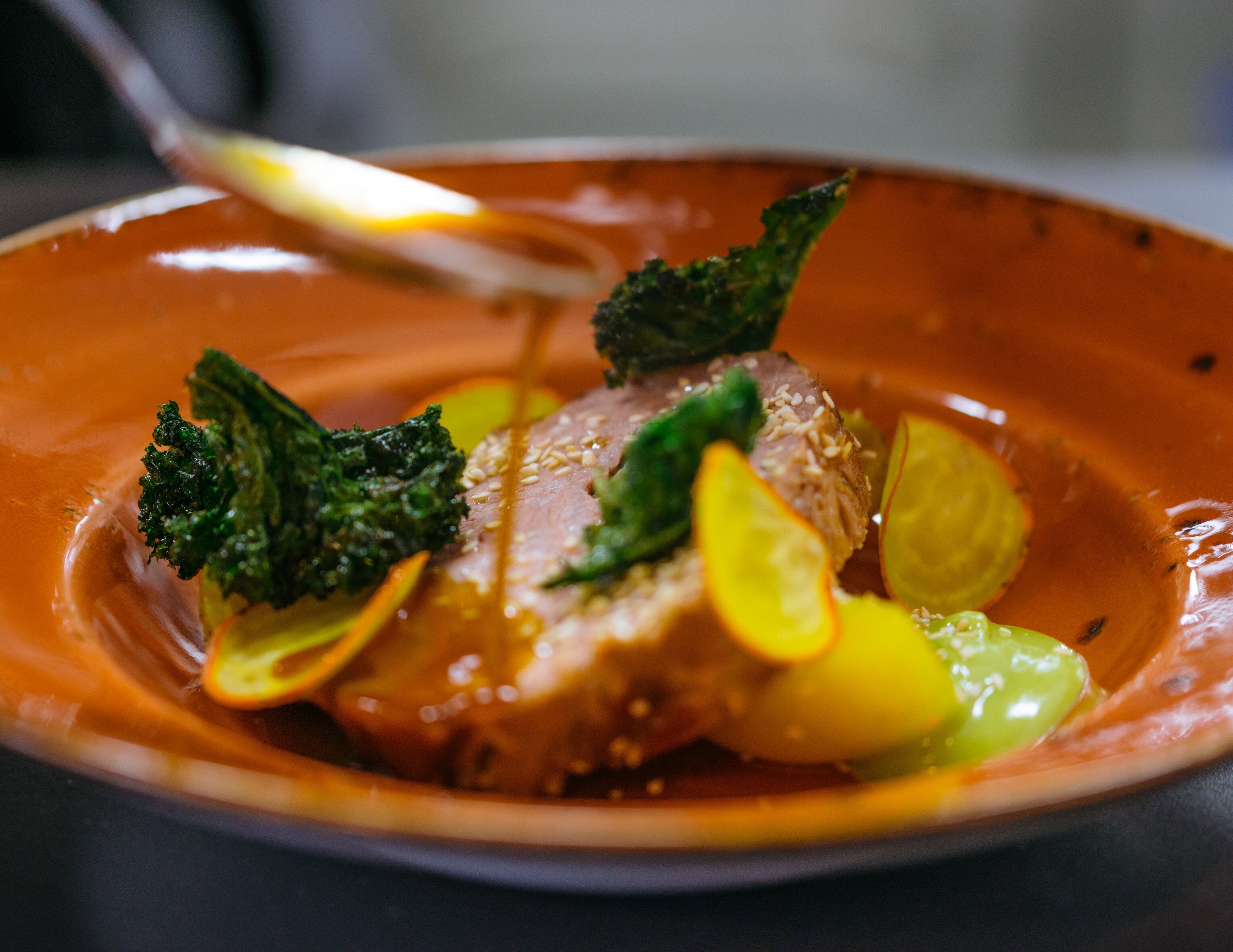 A plate of food with a piece of meat, broccoli, and lemon slices.