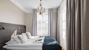 Une chambre d’hôtel avec un lit, un lustre, des rideaux et une vue sur la ville.