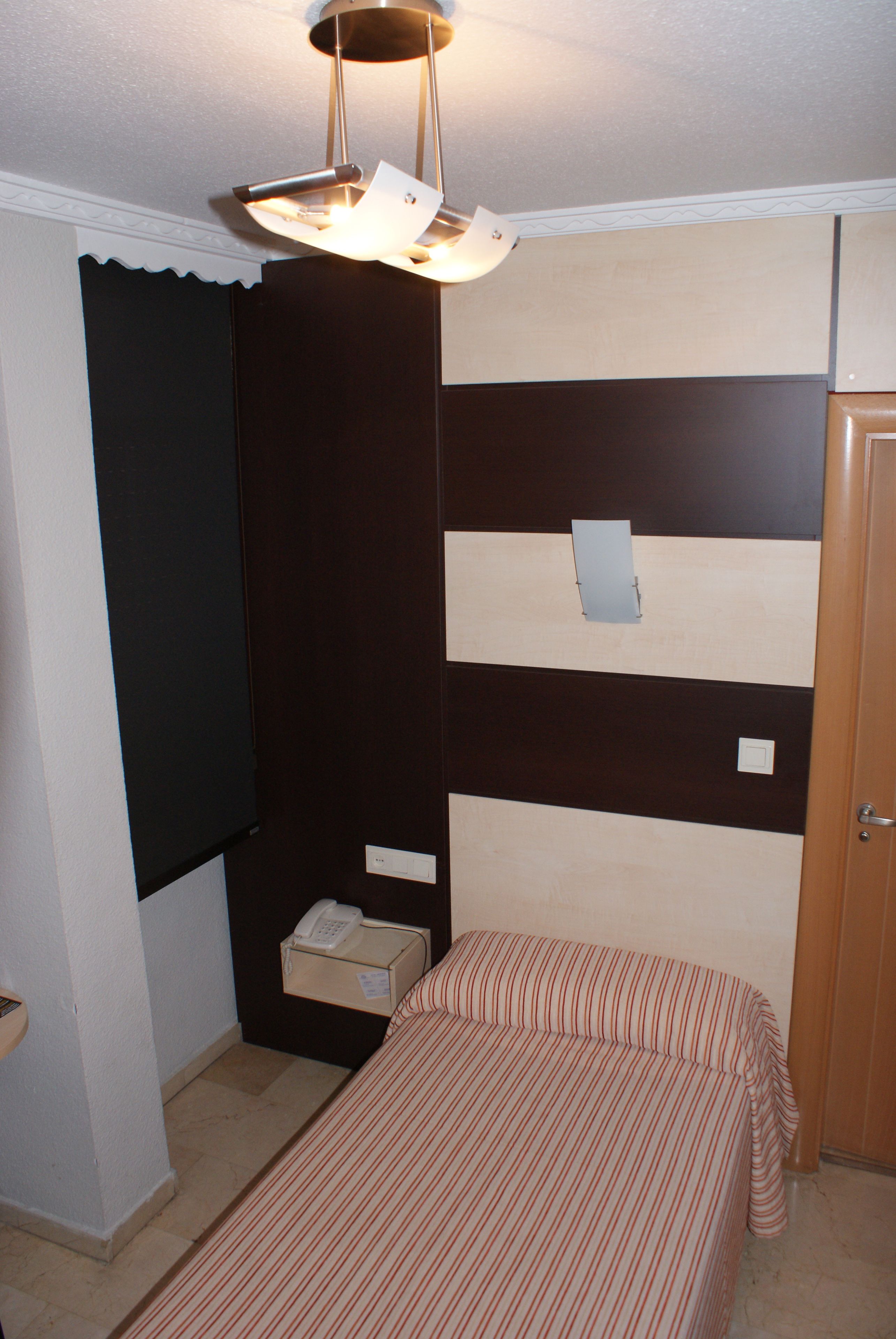 A room with a bunk bed, a bedside table with a lamp, and a telephone.