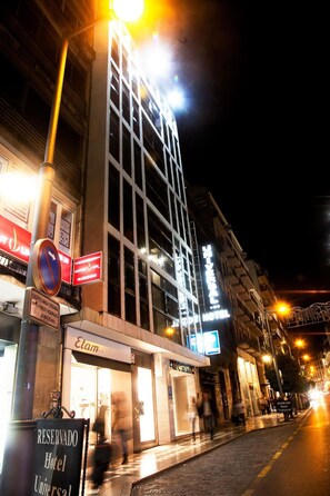 A hotel with a modern facade, illuminated signage, and a street view with pedestrians. - Universal Hotel (Granada)