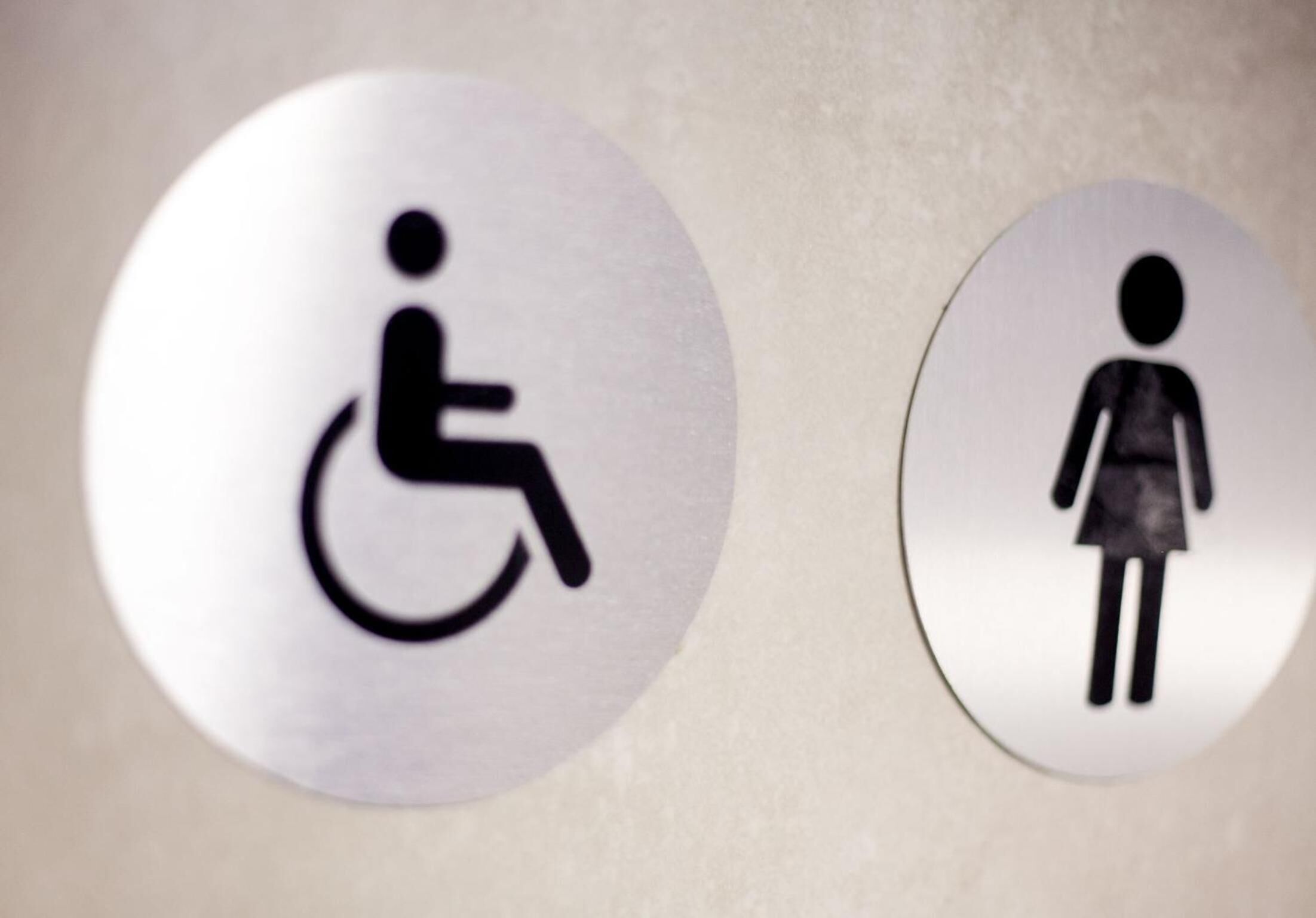 Two restroom signs, one indicating a wheelchair-accessible facility and the other a women's restroom.