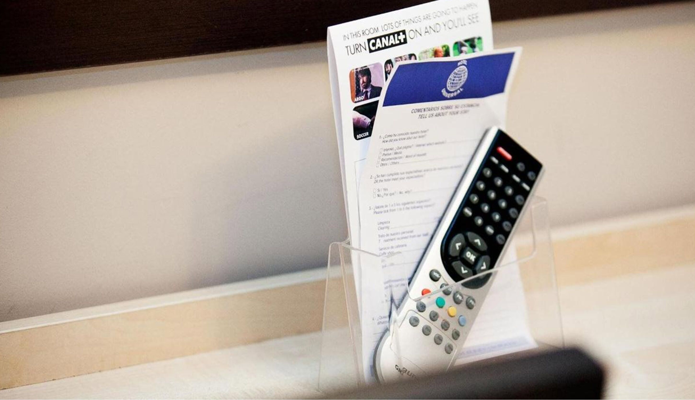 A remote control in a holder with a Canal+ card and a document.