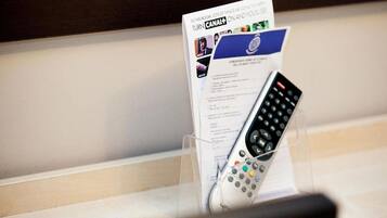 A remote control in a holder with a Canal+ card and a document.