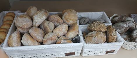 Due cesti di vimini bianco colmi di diversi tipi di pane su un tavolo.