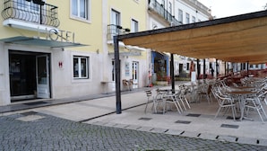 A hotel with outdoor seating and a cobblestone street.
