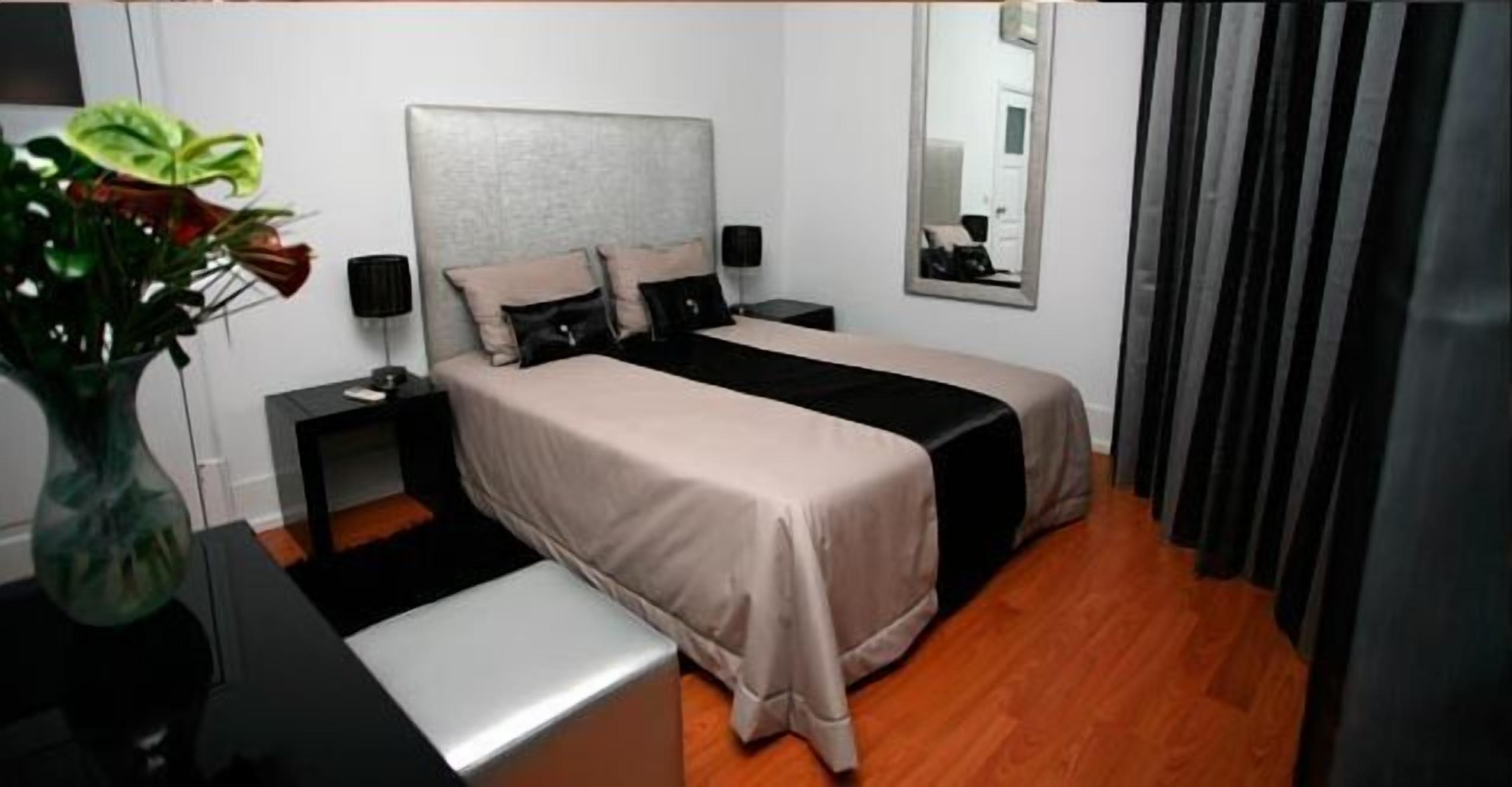 Een slaapkamer met een bed, nachtkastjes, een spiegel en een plant.