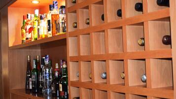 A bar area with wooden shelves holding various bottles and glasses.