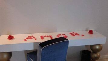 Une table blanche avec des fleurs rouges et une chaise bleue.