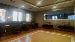 A spacious lobby with a large open area, several seating options including armchairs and a bench, and a reception desk with a counter.