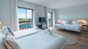 Une chambre d’hôtel avec deux lits, une télévision, un canapé et une vue sur la mer.