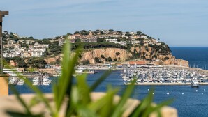Une ville côtière dotée d’un port de plaisance, de bâtiments construits sur une colline et offrant une vue dégagée sur la mer.