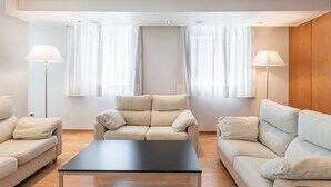 A modern living room with a beige sofa set, a black coffee table, and two floor lamps.