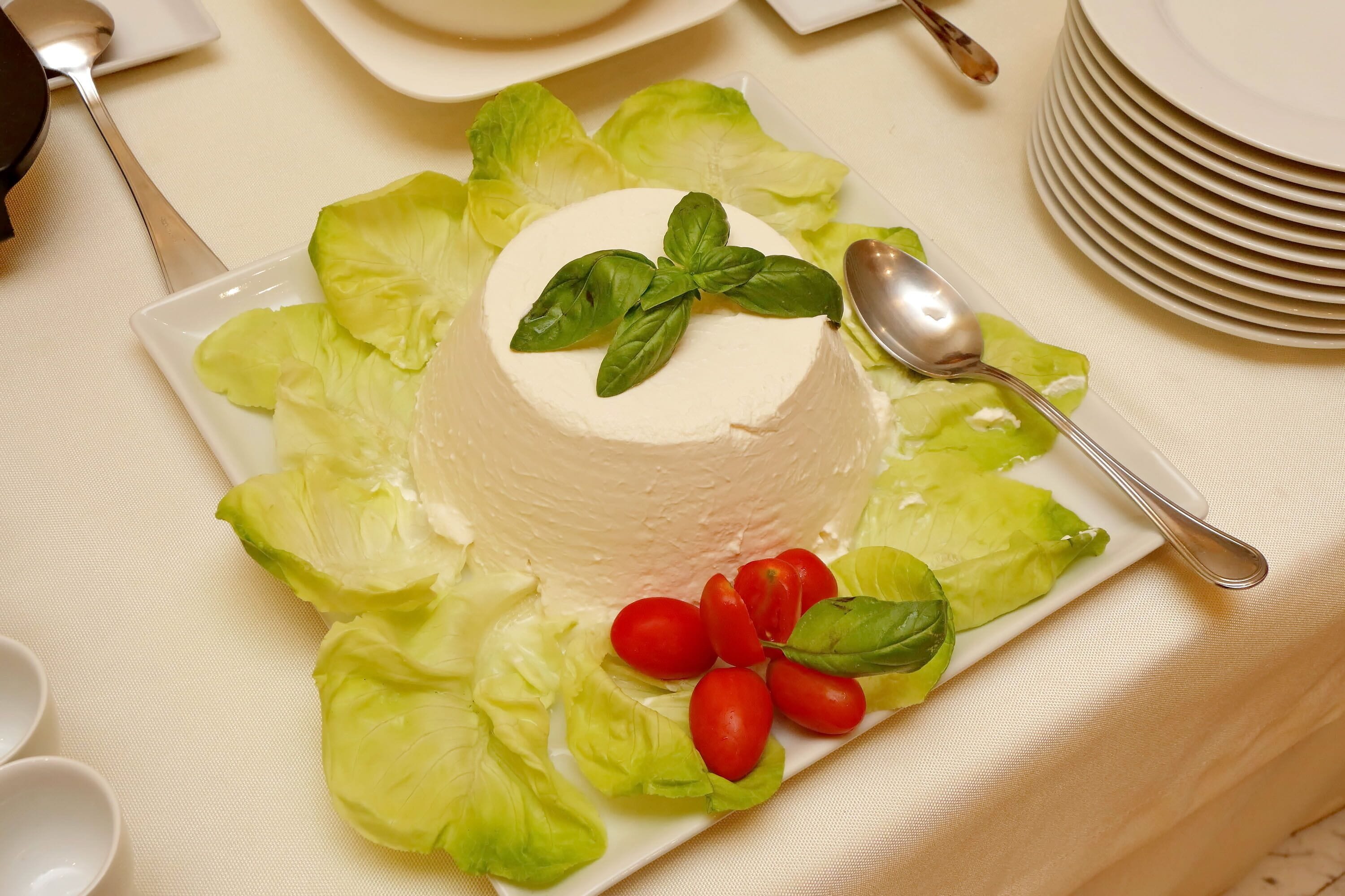 A neatly arranged table with a white plate of food, a spoon, and a stack of plates.