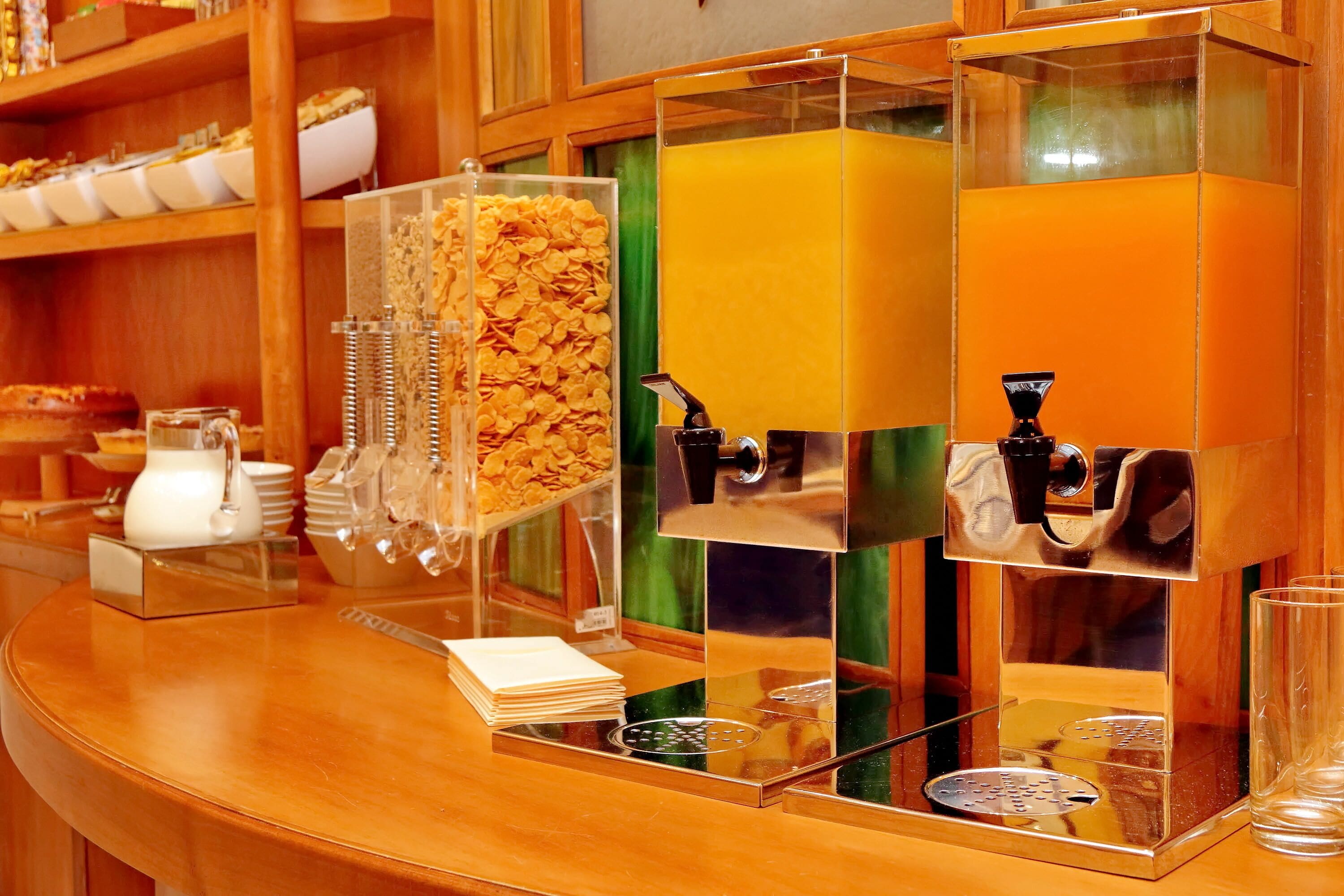 A breakfast bar with cereal, juice, and coffee machines.