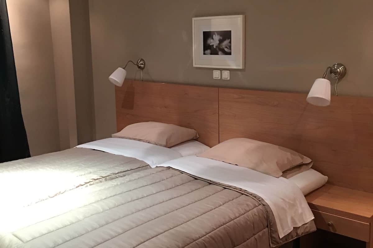 Een hotelkamer met een bed, twee nachtkastjes, een wandlamp en een plafondlamp.