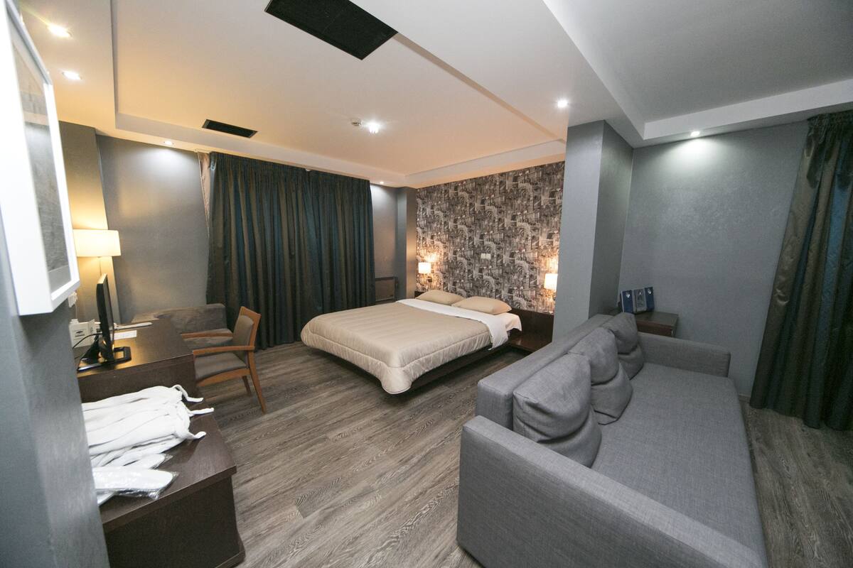 Een moderne hotelkamer met een bed, een bank, een bureau en een wand met behangpapier met een patroon.