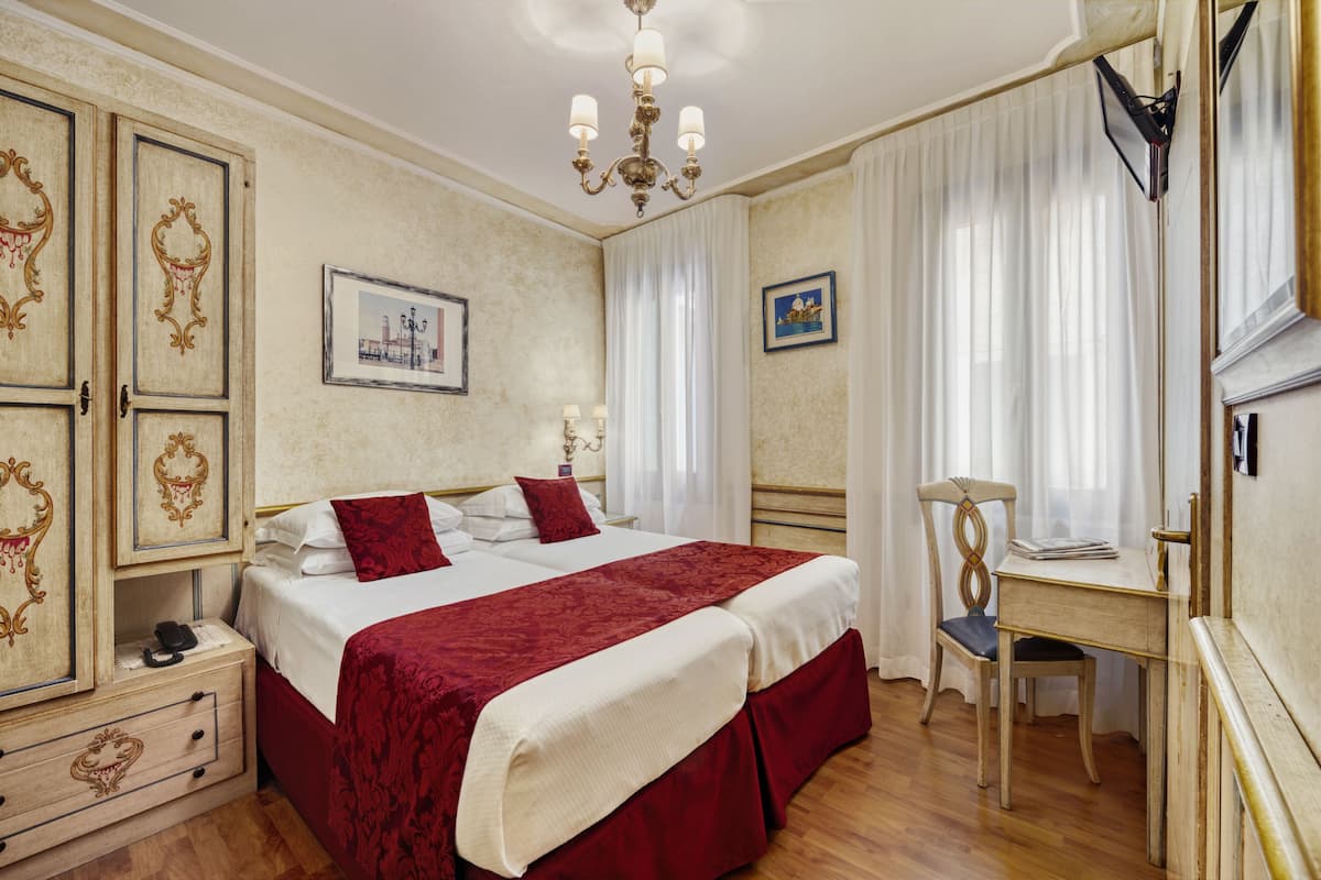A hotel room with a double bed, a desk, and a chair.