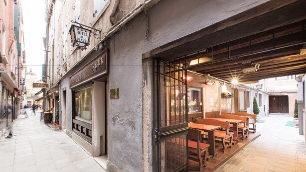 A narrow street with a restaurant on the right, featuring outdoor seating and a view of the street. - Hotel al Piave (Venice)