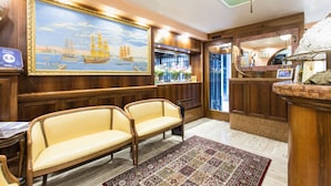 A room with wooden paneling, a large maritime painting, two leather sofas, a patterned rug, and a bar area with a mirror and decorative items. - Hotel al Piave (Venice)