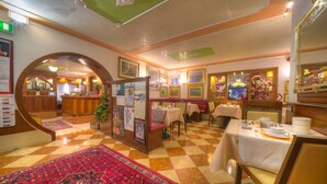 A hotel lobby with a checkered floor, a central seating area with tables and chairs, and a large decorative rug. - Hotel al Piave (Venice)