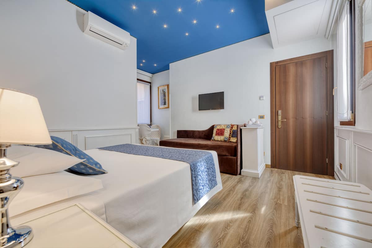 A bedroom with two beds, a TV, and a wooden door.