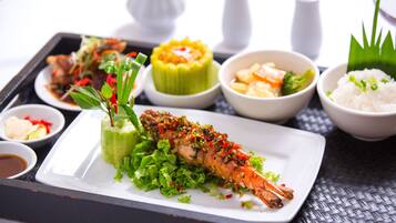 A tray with various dishes including a grilled fish, a green vegetable dish, and bowls of rice and vegetables.