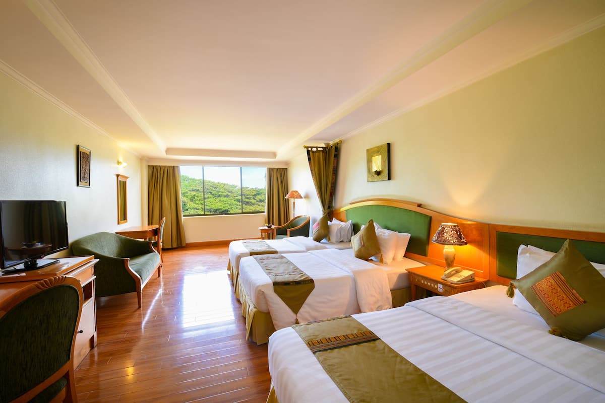 A hotel room with two beds, a desk with a television, and a view of the outdoors.