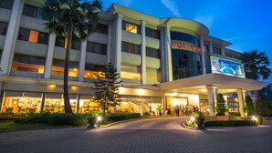 A multi-story hotel with a curved facade, large windows, and a central entrance with a covered area.