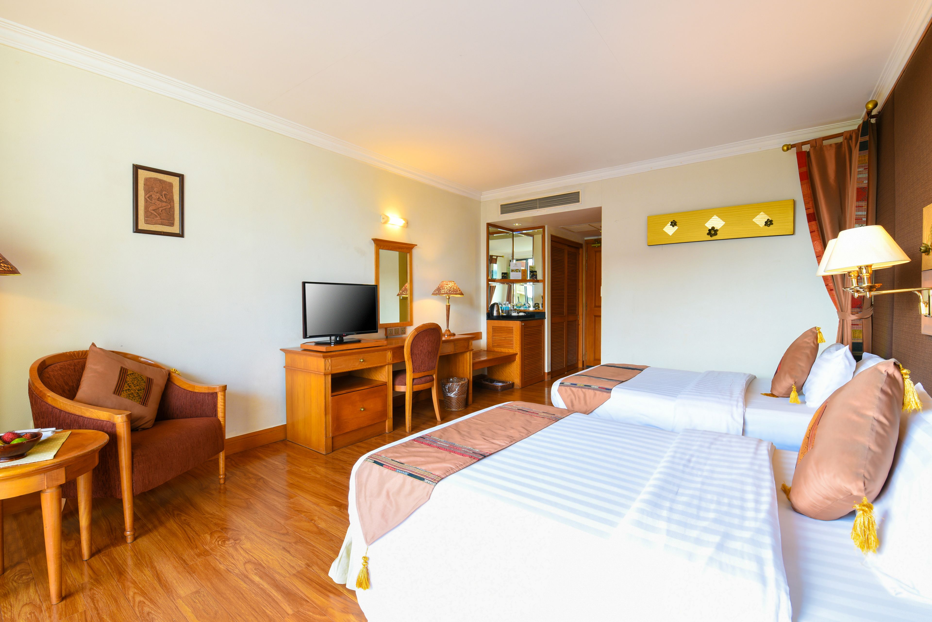 Une chambre d’hôtel avec deux lits, un bureau avec un ordinateur, une chaise et un téléviseur.