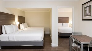 A hotel room with two beds, a desk, and a chair. - El Castell Motel (Monterey)