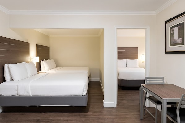 A hotel room with two beds, a desk, and a chair.