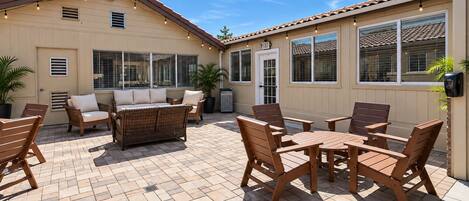 A patio with outdoor furniture, including a sofa and chairs, and a table.
