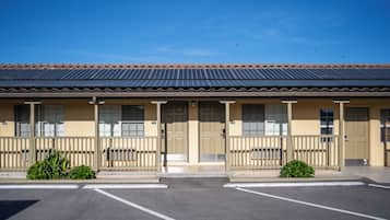 Un motel con techo de tejas, varias puertas y un estacionamiento.