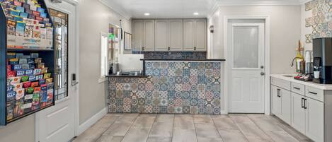 A kitchen with white cabinets, a tiled backsplash, and a refrigerator.