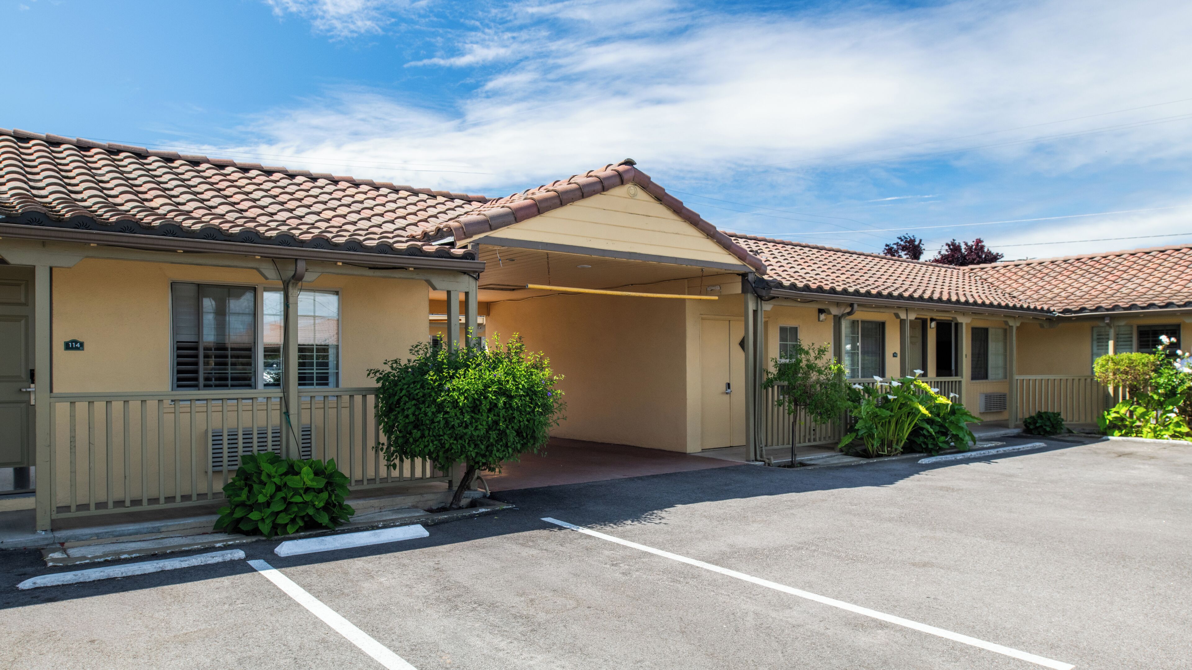 A motel with a covered parking area, a single-story structure, and a small front garden.