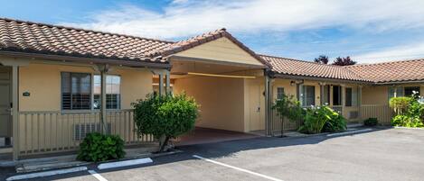 A motel with a covered parking area, a single-story structure, and a small front garden.