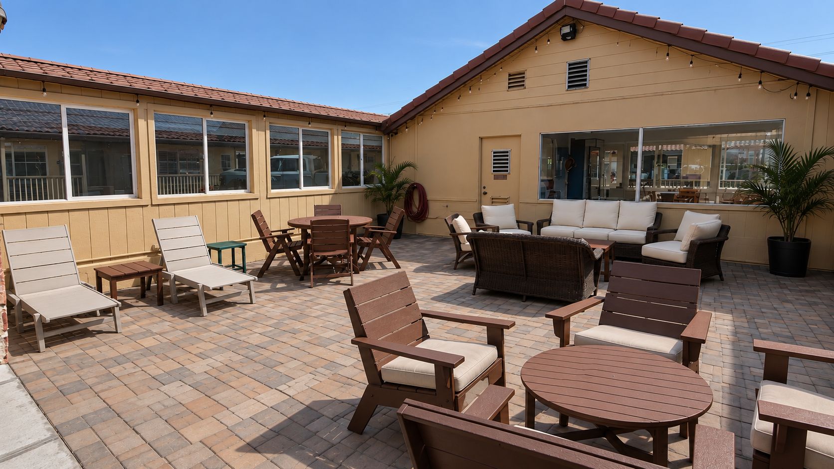 An outdoor patio area with multiple seating options including lounge chairs, a sofa set, and a dining table.